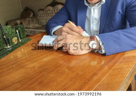 HANDS of a man in a suit at an office table
