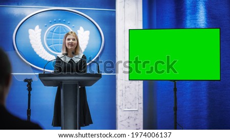 Young Girl Activist Delivering an Emotional and Powerful Speech at Press Conference in Government Building with Green Screen Mock Up on Display. Child Speaking to Congress at Summit Meeting. Royalty-Free Stock Photo #1974006137