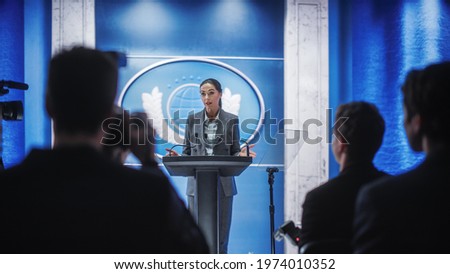 Organization Female Representative Speaking at a Press Conference in Government Building. Press Office Representative Delivering a Speech at a Summit. Minister Speaking to a Congress Hearing. Royalty-Free Stock Photo #1974010352