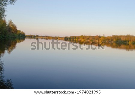 wide river at sunset and trees on the shore