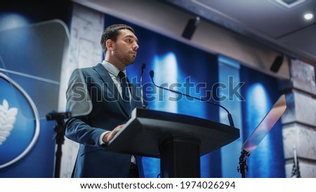 Portrait of an Young Organization Representative Speaking at Press Conference in Government Building. Press Officer Delivering a Speech at Summit. Minister Speaking at Congress Hearing. Royalty-Free Stock Photo #1974026294