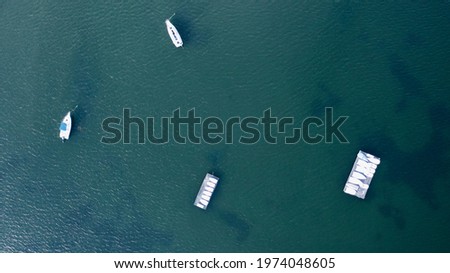 A top down shot directly over boats wrapped in white stored on a barge in green waters. It was taken on a sunny morning with a drone camera.