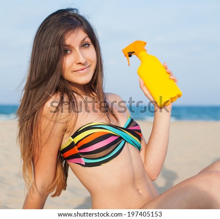 pretty girl holding a sun cream in the beach
