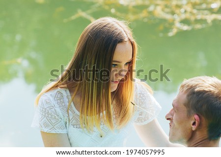 A couple in love is sitting by the lake in the park.A beautiful woman looks at a young man