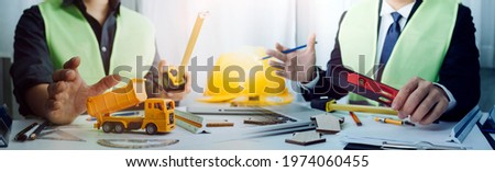 engineer working at a drawings of house in office for discussing. Engineering tools and construction concept.