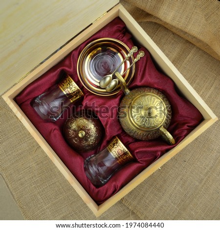 Close up photo of a traditional Turkish tea set with colored glasses and bronze copper hand crafted tea pot in gift box.