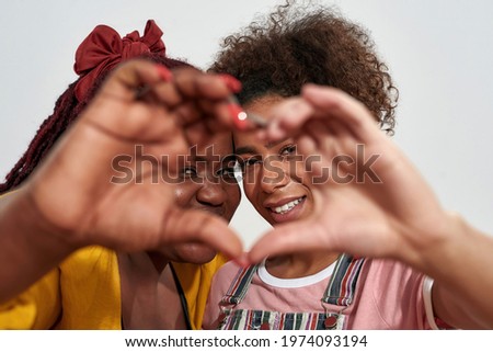 Picture of a two black women making a heart with hands and smiling from inside. Isolated over the white background