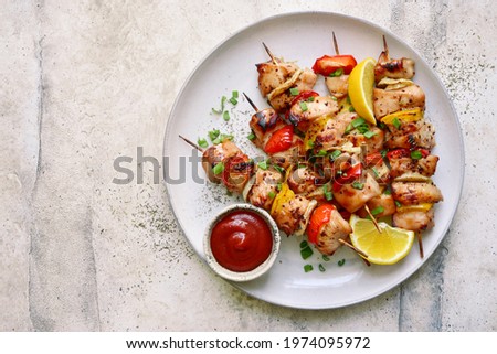 Chicken kebab skewers on a plate over light grey slate, stone or concrete background . Top view with copy space. Royalty-Free Stock Photo #1974095972