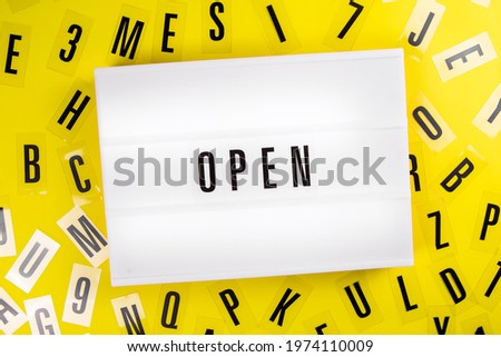 Lightbox with text OPEN on yellow background with black letters around. Concept of reopening, back to normal, business, cafe, restaurants, entertainment service, open content, library, knowledge base