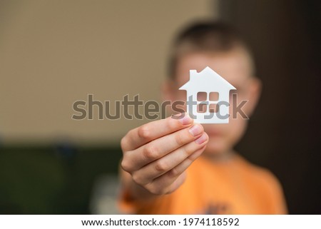Orphanage, children in the orphanage. The child is holding a small house-shaped figurine, close-up. Adoption concept. Banner, place for text Royalty-Free Stock Photo #1974118592