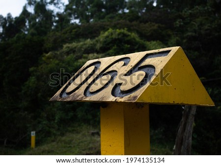 Road sign with number 65 in the middle of the forest vegetation