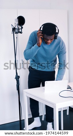Man wearing headphones standing in front of a microphone - Recording A Song. High quality photo