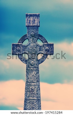 Old Victorian gravestone cross at Cashel cemetery in Ireland processed with colour process filter.