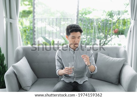 A handsome boy holds a transparent capsule, pills or vitamins and looks at it Royalty-Free Stock Photo #1974159362