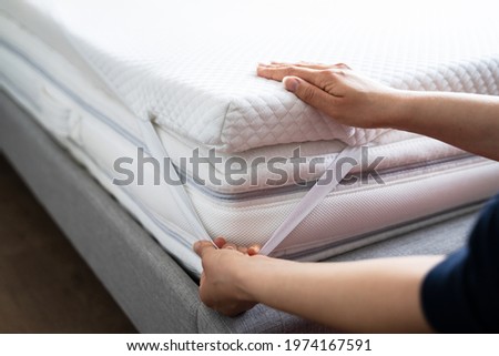 Mattress Topper Being Laid On Top Of The Bed Royalty-Free Stock Photo #1974167591