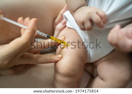 asian baby infant get fever and apply cool patch on forehead getting injection for vaccination on leg by doctor. cold pad gel healing temperature. baby sick and crying. Royalty-Free Stock Photo #1974175814