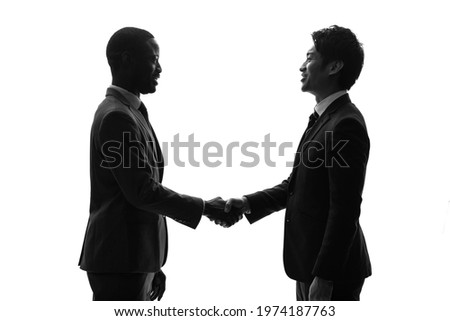 Silhouette of black and asian people shaking hands. Global business.