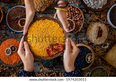 Various of legumes at the hands of two women in the bowl. Top view picture of many legumes.