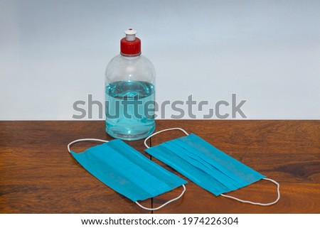 A bottle of hand sanitizer and surgical face masks kept on a table with copy space