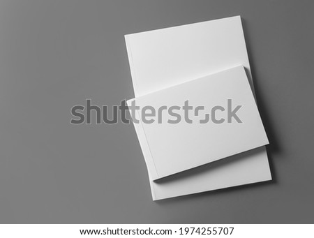 Brochures with blank covers on light grey background, top view. Space for text