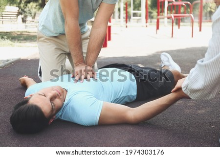 Passerby performing CPR on unconscious man outdoors. First aid Royalty-Free Stock Photo #1974303176