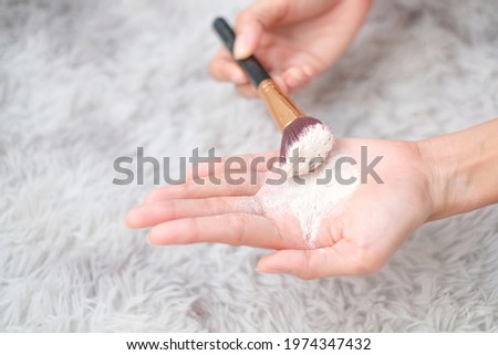 Close up woman holding talc make up and brush on carpet background, beauty concept. Royalty-Free Stock Photo #1974347432