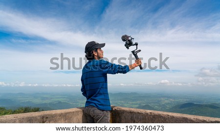 Young asian blogger or vlogger looking at camera and talking on video shooting with technology. Social media influencer people or content creator. Royalty-Free Stock Photo #1974360473