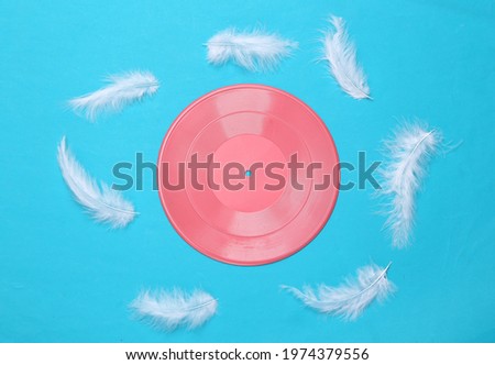 Creative music layout. Feathers and pink vinyl record on blue background. Top view, Flat lay. Concept art
