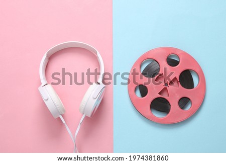 Pink retro audio reel and headphones on blue pink background. Minimalism music concept. Top view