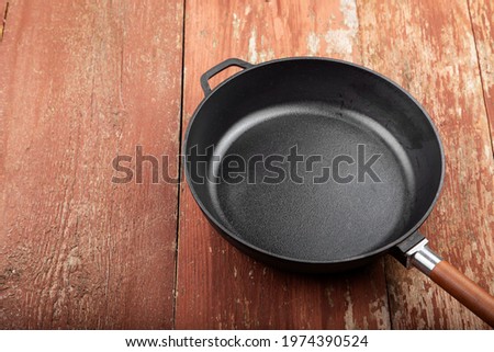 Empty cast iron skillet on a red wooden background.