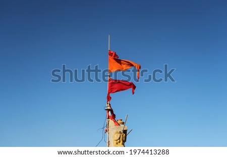 Orange flags fluttering at the top of a Hindu temple in India with a blue sky in the background