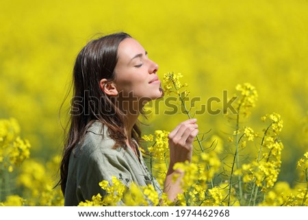 Profile of a woman smelling flowers in a yellow field Royalty-Free Stock Photo #1974462968