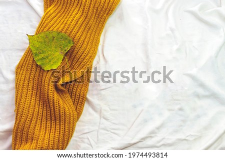 Bedding with mustard warm plaid and maple leaf. Copy space. Flat lay, top view