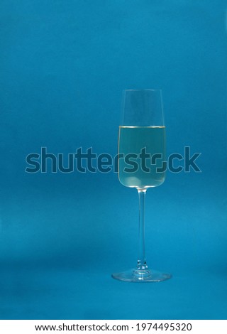 a glass of white wine isolated on blue background. Image contains copy space