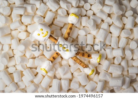A man from marshmallow on the background of a large number of marshmallows. A collage of sweets. Flat lay.