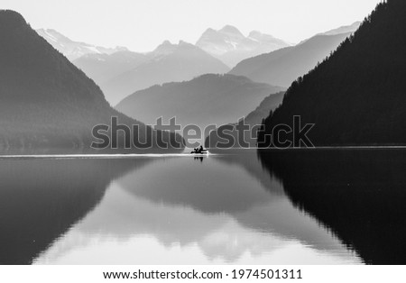 Mountain and lake reflection with fishing boat at sunrise in Golden Ears Provincial Park on Lake Alouette British Columbia black and white and color