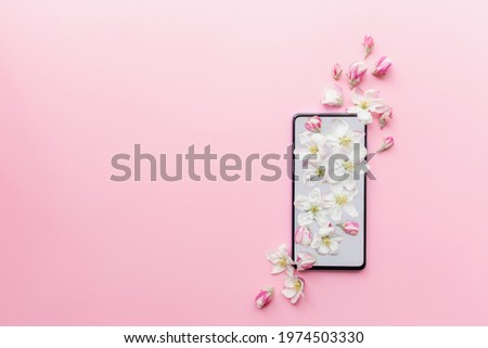 Pink flat lay concept of fresh spring and romantic content, phone, blossom