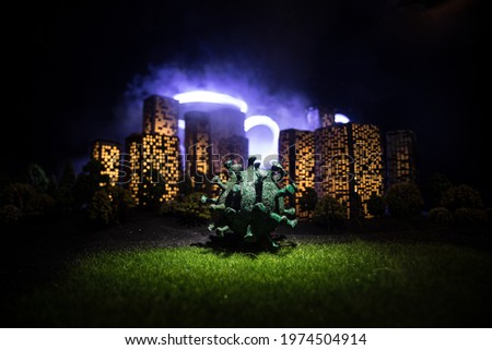 Cartoon style city buildings. Realistic city building miniatures with lights. Big Corona virus miniature in the city at night. Stay home stay safe or coronavirus pandemic concept. Selective focus. Royalty-Free Stock Photo #1974504914