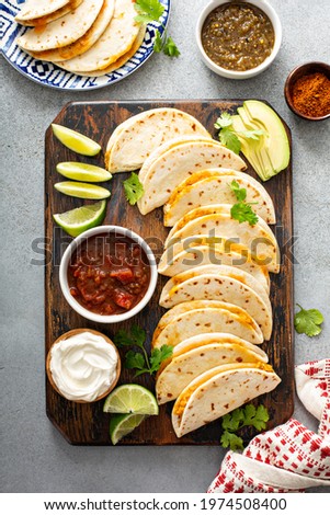 Baked tacos with pulled chicken and cheese served with sour cream and salsa