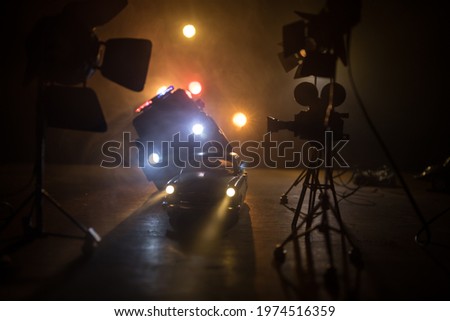 Action movie concept. Police cars and miniature movie set on dark toned background with fog. Police car chasing a car at night. Scene of crime accident. Selective focus