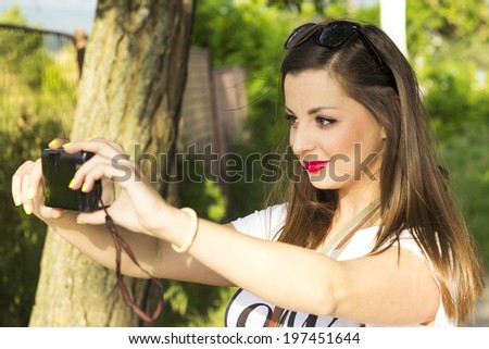Young women taking a self portrait with camera in park