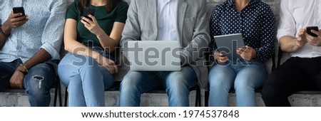Diverse group of customers sitting in line, holding digital gadgets, using online apps and services on smartphone, laptops, tablets for work, checking messengers, chatting on social media. Banner Royalty-Free Stock Photo #1974537848