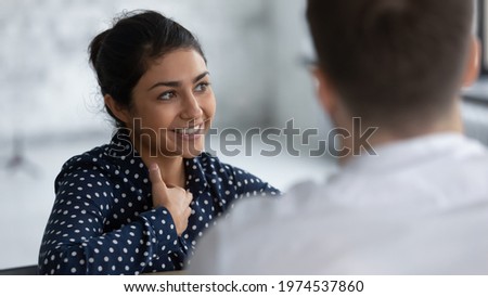Happy Indian female employee discussing project on corporate briefing, brainstorming with colleagues. Smiling job candidate talking to recruiter or employer on interview. Client and consultant meeting Royalty-Free Stock Photo #1974537860