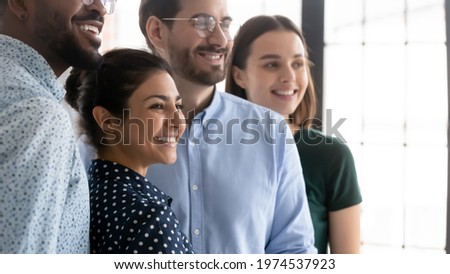 Millennial workers of different races celebrating accomplished project. Diverse happy employees standing together. Indian female business leader smiling and posing with colleagues. Candid shot Royalty-Free Stock Photo #1974537923