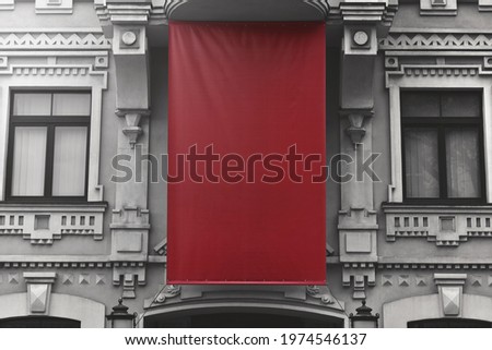 blank red textile banner of outdoors advertising is hang on facade old building