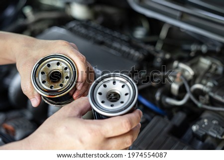 Close up used oil filter in hand a man compare with the new oil filter service concept of oil in the check period Royalty-Free Stock Photo #1974554087