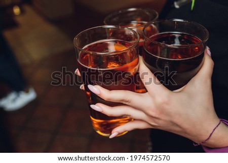Woman holding three glasses of beer bartender.