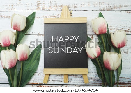 Happy Sunday text and Bouquet of tulips on white wooden background