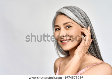 Portrait of gorgeous happy middle aged mature asian woman, senior older 50 year lady looking at camera touching her face isolated on white. Ads of lifting anti wrinkle skin care, spa. Copy space. Royalty-Free Stock Photo #1974575039