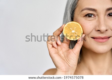 Beauty. Closeup portrait of middle aged beautiful Asian 50s woman with perfect natural makeup holding citrus juicy lemon fruit. Vitamin C cosmetics whitening treatment advertising concept. Copy space. Royalty-Free Stock Photo #1974575078